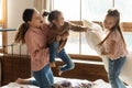 Playful mother enjoying morning pillow battle with children. Royalty Free Stock Photo