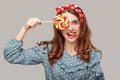 Playful pinup girl ruffle blouse covering eye with sweet spiral candy looking at camera, showing tongue out