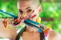 Playful portrait of a young gorgeous female painter artist, with hands covered in paint, looking and smiling at camera. Royalty Free Stock Photo