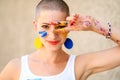 Playful portrait of a young gorgeous female painter artist, with hands covered in paint, looking and smiling at camera. Royalty Free Stock Photo