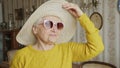 playful and pretty senior Caucasian woman with pink sunglasses and a hat smiling happily medium closeup indoor seniority