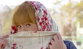 Playful red-haired girl closes half of his face with a scarf.