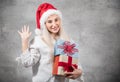 Playful santa woman holding christmas gifts isolated on gray background. Happy young girl wearing red santa hat and holding Royalty Free Stock Photo