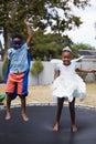 Playful siblings in costumes jumping on trampoline