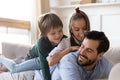 Playful small kids siblings lying on fathers back at home. Royalty Free Stock Photo