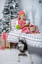 Happy cute little girl dressed in striped pajamas sitting in decorated New Year room at home. Royalty Free Stock Photo