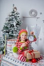 Happy cute little girl dressed in striped pajamas sitting in decorated New Year room at home. Royalty Free Stock Photo