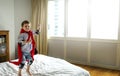 Playful superhero little boy jumping on the bed