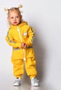 Playful toddler girl dressed in a warm yellow sports jumpsuit. Royalty Free Stock Photo