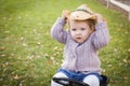 Playful Toddler Wearing Cowboy Hat and Playing on Toy Tractor Outside Royalty Free Stock Photo