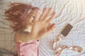 Playful woman hides from camera closing lens by palm on comfortable bed Royalty Free Stock Photo