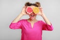 Playful woman holding halves of citrus fruits, covering eyes Royalty Free Stock Photo