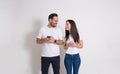 Playful woman peeking at boyfriend's smart phone and trying to read his messages on white background Royalty Free Stock Photo