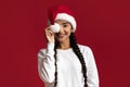 Playful Young Arab Female Wearing Santa Hat Covering Eye With Pompom Royalty Free Stock Photo