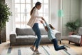 Happy young mom and little daughter dancing at home