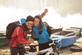 Playful young couple riding mountain bikes by the river or lake posing for a selfie