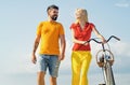 Playful young man with his beautiful girlfriend on the love way. Summer woman with retro bike on blue sky background Royalty Free Stock Photo