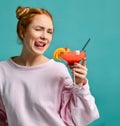 Playful young woman holds a glass of tropic cocktail strawberry margarita and winks