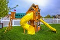 Playground at the backyard of a home inside a white wooden fence.