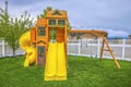 Playground on a backyard with view of homes and cloudy sky beyond the fence