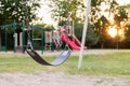 Playground for children in the public park during sunset. Selective focus on the swing Royalty Free Stock Photo