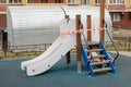 A playground with a children`s slide wrapped in barrier tape, the ban goes onto the street. Sanitization of the playground,