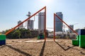 Playground with empty swings in shopping center with buildings in blurred background Royalty Free Stock Photo