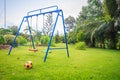 Playground equipment in the backyard for kids with soccer goal net and football on green grass field background.