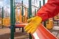 playground equipment being sanitized by a glove-clad hand