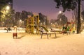 The playground in the night park with lanterns in the winter. Benches in the park during the winter season at night. Illumination Royalty Free Stock Photo