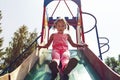 Playground or play area is an area designed for children to play, indoors or outdoors, A little girl rolls down an old metal slide Royalty Free Stock Photo