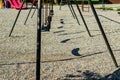 Playground rubber seat swings showing their shadows Royalty Free Stock Photo