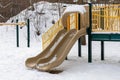 Playground slide in park without kids, covered with snow in winter season Royalty Free Stock Photo