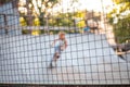 Playground with slides behind a mesh fence. Boys ride skateboards and scooters, blurred background Royalty Free Stock Photo