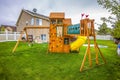 Playground structure with slide swings playhouse tower and climbing wall Royalty Free Stock Photo