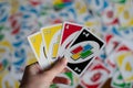 Playing american card game Uno, holding game cards in female hand. Deck of Uno game cards scattered all over on a table. American Royalty Free Stock Photo