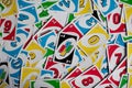 Playing american card game Uno, holding game cards in female hand. Deck of Uno game cards scattered all over on a table. American Royalty Free Stock Photo