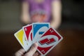 Playing american card game Uno, holding game cards in female hand.