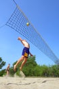 Playing beach volleyball - fat man jumps high to spike the ball Royalty Free Stock Photo