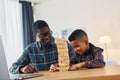 Playing bricks game. African american father with his young son at home