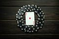 Playing card ace of diamonds with black chips from winning on a vintage table in a clubhouse. Low key concept of luck symbol in Royalty Free Stock Photo