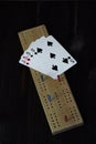 Playing cards and cribbage board on black background