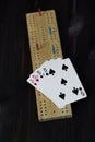 Playing cards and cribbage board on black background