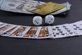 Playing cards, dices and money on a black background.