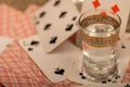 Playing cards and a glass of vodka on a table covered with coarse burlap Royalty Free Stock Photo