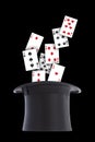 Playing cards spill out and scattered from a black top hat upside down on black background Royalty Free Stock Photo