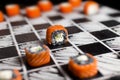 Japanese Sushi with salmon, cucumber and Cream cheese on hand drawn chessboard. Sushi with black rice Royalty Free Stock Photo