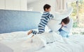 Playing, dad and son in pillow fight on bed, fun quality time and man bonding with child at home. Smile, happy and play