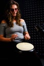 Playing on ethnic African percussion instrument, horizontal photo. A young woman plays a drum sitting on the floor in a recording