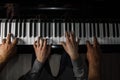 Playing four male hands on the piano. palms lie on the keys and play the keyboard instrument in a music school. student learns to Royalty Free Stock Photo